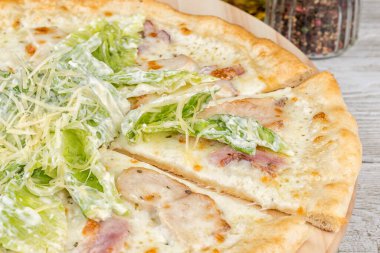 Yuvarlak bir tahtada dilimlenmiş Sezar pizzası. Yakın çekim.