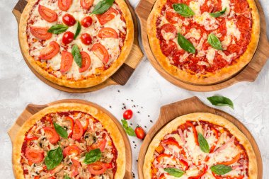 Yukarıdan ahşap tahtalarda dört çeşit pizza.