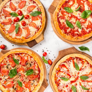 Yukarıdan ahşap tahtalarda dört çeşit pizza.