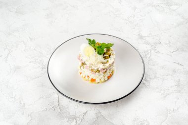 Beyaz yuvarlak tabakta Olivier salatası. Yukarıdan yakın çekim.