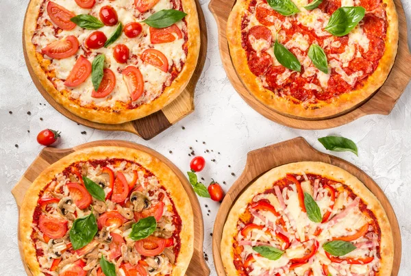 Yukarıdan ahşap tahtalarda dört çeşit pizza.