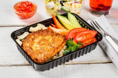 Makarnalı pirzola, siyah kabın içinde sebzeler. Yakın çekim.