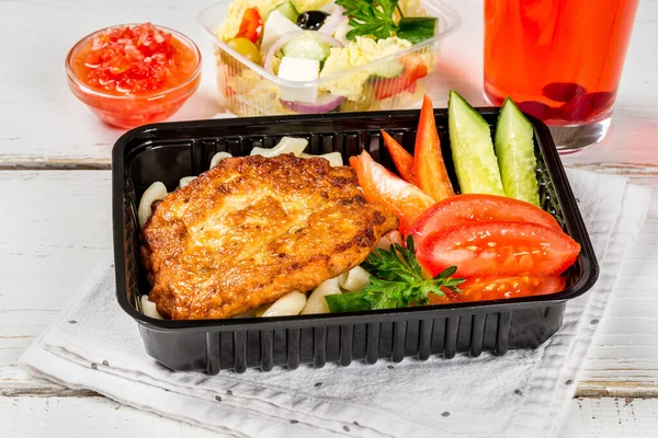 Cutlet with pasta, vegetables in a black container. Close-up shot