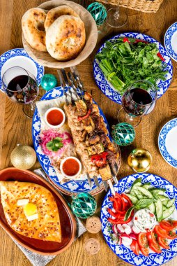 Khachapuri, barbekü, salata, sebze ve şarapla dolu bir masa.