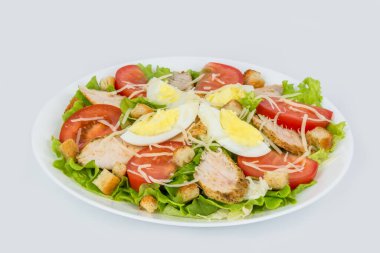 Arka planda beyaz bir tabakta taze otlarla Sezar salatası.