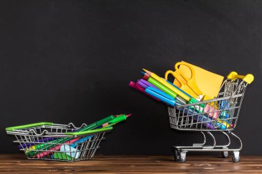 Okula geri dönme konsepti. Mesaj için yer var. Ofis malzemeleri bir alışveriş sepetinde tahtanın yanındaki tahta masada.