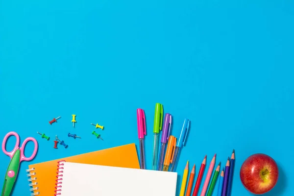 Le concept de retourner à l'école. Fournitures scolaires colorées, cahiers, crayons, stylos, trombones, peinture sur fond bleu. Espace pour le texte. La vue du haut — Photo
