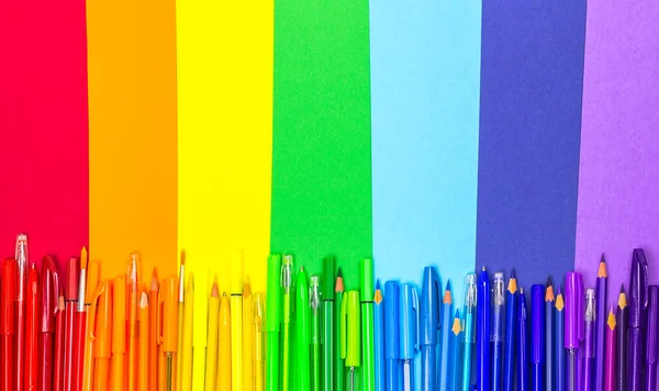 De vuelta a la escuela. Los útiles escolares se presentan en forma de arco iris. Bolígrafos, lápices, marcadores de colores del arco iris están en papel de colores. La vista desde arriba, lugar para el texto — Foto de Stock