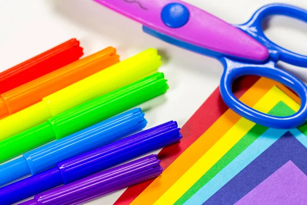 Je retourne à l'école. Les fournitures scolaires sont disposées sous forme d'arc-en-ciel. Papier coloré, marqueurs arc-en-ciel et ciseaux sont sur la table sur un fond blanc. La vue du haut — Photo