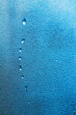 Bardağa mavi su damlaları, soyut arka plan, büyük ve küçük damlalar. Metin için boşluk