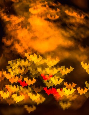 Cadılar Bayramı için soyut bir arkaplan, kırmızı, sarı ve turuncu renkli yarasalar şeklinde bokeh. Metin için boşluk