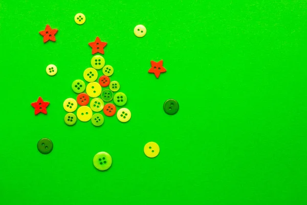 Green and red buttons are in the shape of a Christmas tree on a green background, with round buttons and stars around them. The view from the top