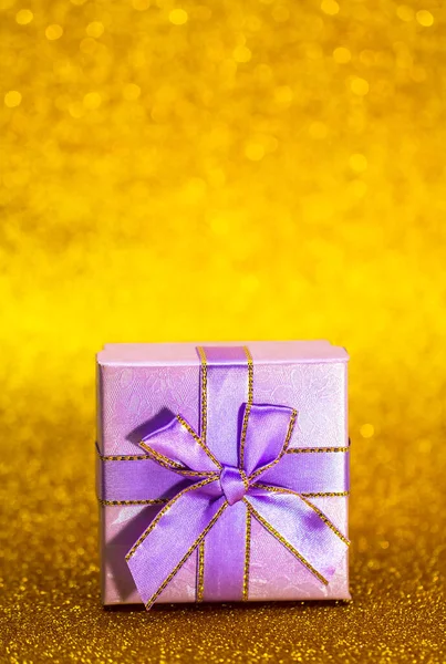 Caja de regalo púrpura con fondo bokeh dorado. Tarjeta de felicitación de vacaciones. Navidad, año nuevo, cumpleaños. Espacio para texto — Foto de Stock