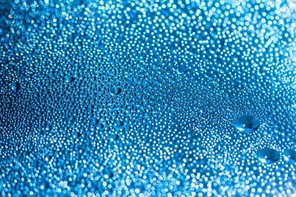 A água azul cai sobre o vidro, fundo abstrato, grandes e pequenas gotas. Espaço para texto — Fotografia de Stock
