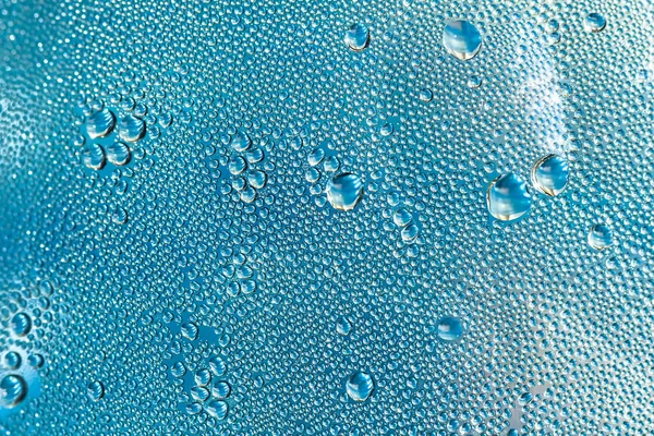 A água azul cai sobre o vidro, fundo abstrato, grandes e pequenas gotas. Espaço para texto — Fotografia de Stock
