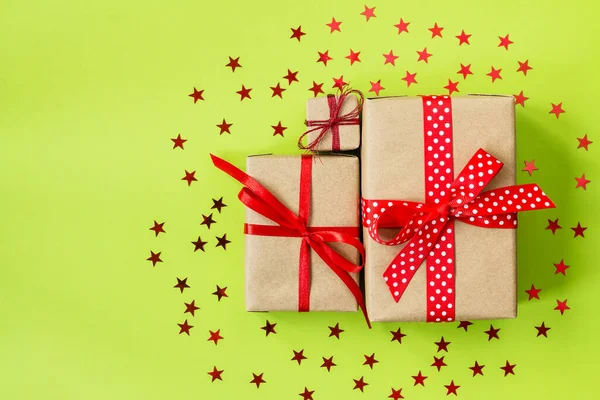 Conjunto de cajas de regalo envueltas en papel artesanal con cintas rojas sobre un fondo verde. Tarjeta de felicitación de vacaciones. Navidad, Año Nuevo, cumpleaños — Foto de Stock