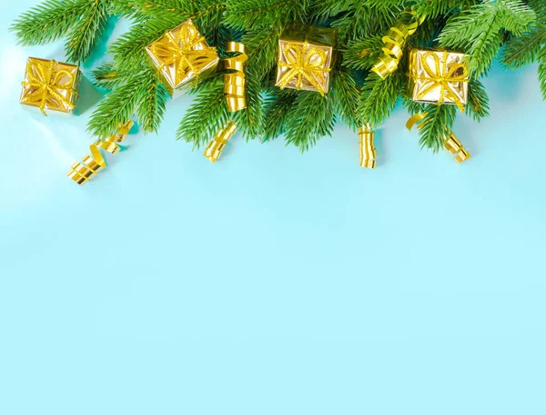 Sada zlatých dárkových krabic a pruh leží na smrkových větvích na modrém pozadí v podobě rámu. Pozdrav na dovolenou. Vánoce, Nový rok — Stock fotografie