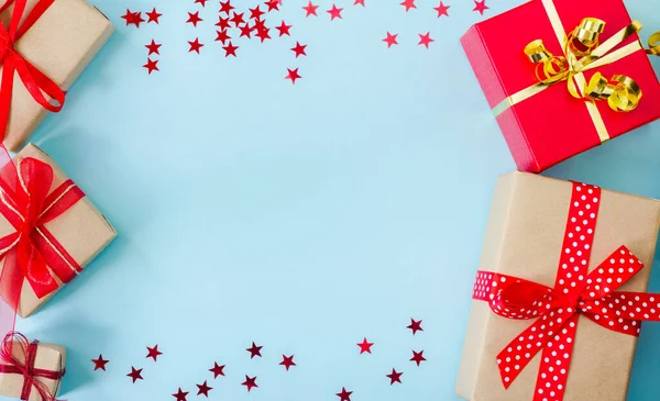 Set di scatole regalo rosse e beige con coriandoli a forma di stelle su sfondo blu, cornice. Biglietto di auguri. Natale, Anno nuovo, compleanno — Foto Stock