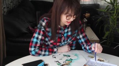 Gözlükmavi gözlü genç bir kız hevesle çizer