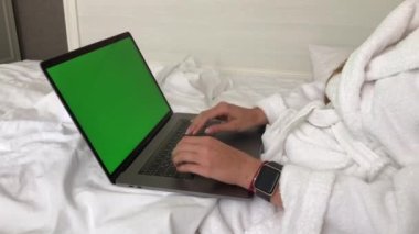  Kadın bornozla otelde yatarken MacBook Pro 'da çalışıyor. Yüksek kalite 4k görüntü