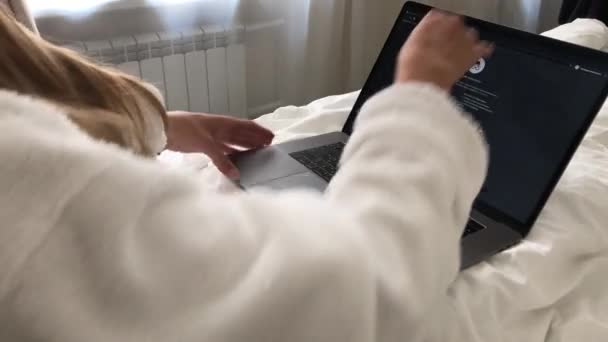 MOSKVA CITY, RUSKO - 10.08.2020: Žena pracující na makbooku při ležení v posteli v hotelu v županu — Stock video