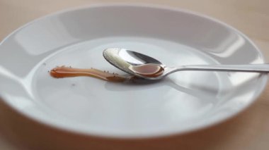 Karıncalar beyaz bir tabakta bir kaşık bal üzerinde sürünürler.