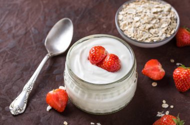 Cam kase çilek ve yulaf gevreği rustik zemin üzerine beyaz yoğurt.