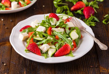 Doğal rustik masa üzerinde beyaz tabakta sebze taze çilek salatası.