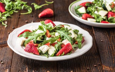 Doğal rustik masa üzerinde beyaz tabakta sebze taze çilek salatası.