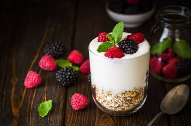 Müsli ve ahududu cam kase rustik ahşap arka plan üzerinde beyaz yoğurt.