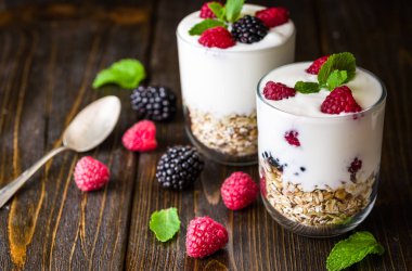 Müsli ve ahududu cam kase rustik ahşap arka plan üzerinde beyaz yoğurt.