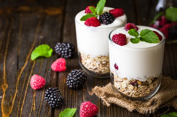 Müsli ve ahududu cam kase rustik ahşap arka plan üzerinde beyaz yoğurt.