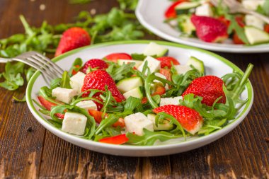 Doğal rustik masa üzerinde beyaz tabakta sebze taze çilek salatası.