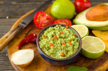 Madde ile doğal rustik masa mavi kase guacamole: limon, domates, biber çevresinde.