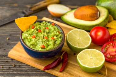 Madde ile doğal rustik masa mavi kase guacamole: limon, domates, biber çevresinde.