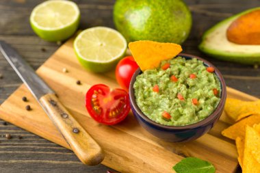 Madde ile doğal rustik masa mavi kase guacamole: limon, domates, biber çevresinde.