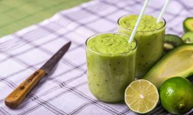 Avokado ile beyaz arka plan, limon sağ tarafında üzerinde yeşil smoothie.