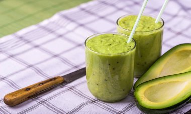 Avokado ile beyaz arka plan, limon sağ tarafında üzerinde yeşil smoothie.