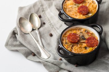 Slovak Noel Ulusal lahana çorbası sosisli masa örtüsü arka plan üzerinde iki küçük siyah tencere.