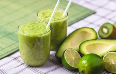 Avokado ve limon sağ tarafındaki yeşil zemin üzerine yeşil smoothie.