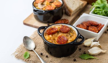 Slovak Noel Ulusal lahana çorbası sosisli Jüt arka plan üzerinde iki küçük siyah tencere.