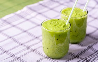 Avokado, limon ve kivi yaptığı beyaz masa örtüsü üzerinde yeşil smoothie.