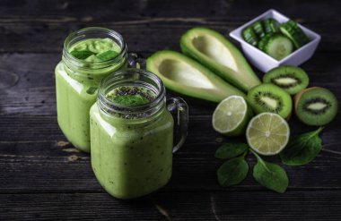 Avokado, ıspanak, limon ve kivi sağ tarafındaki koyu zemin üzerine yeşil smoothie.