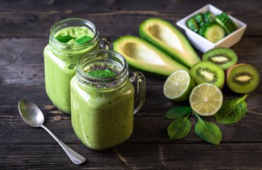 Avokado, ıspanak, limon ve kivi sağ tarafındaki koyu zemin üzerine yeşil smoothie.