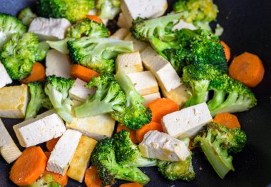 Brokoli ve havuç wok içinde kızarmış tofu.