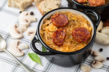 Slovak Noel Ulusal lahana çorbası sosisli masa örtüsü arka plan üzerinde siyah küçük tencerede.