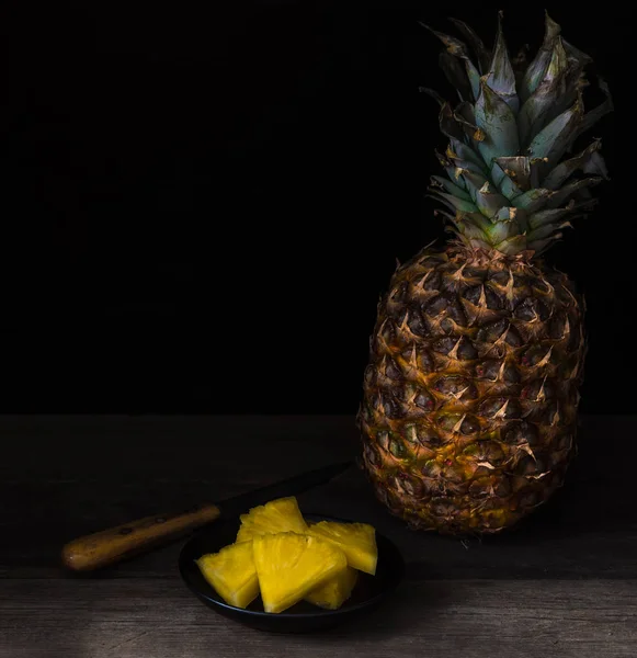 Ananas tranché sur fond noir isolé sur vieux bureau rustique . — Photo