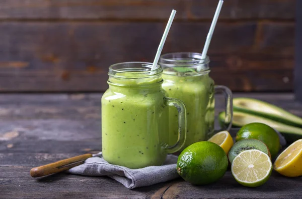 Grön smoothie på grön bakgrund görs av avokado, citron och kiwi. — Stockfoto