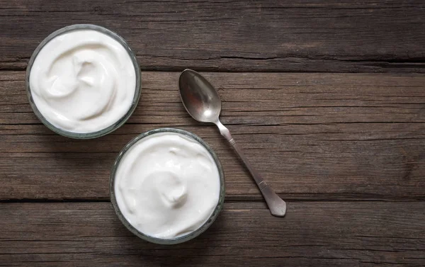 Dua mangkuk kaca dengan yogurt putih di meja kayu tua . — Stok Foto