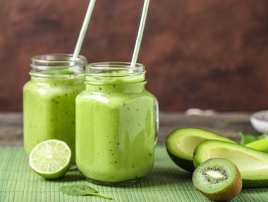 Yeşil smoothie avokado, limon ve doğal ahşap zemin üzerine kivi tarafından yapılan.